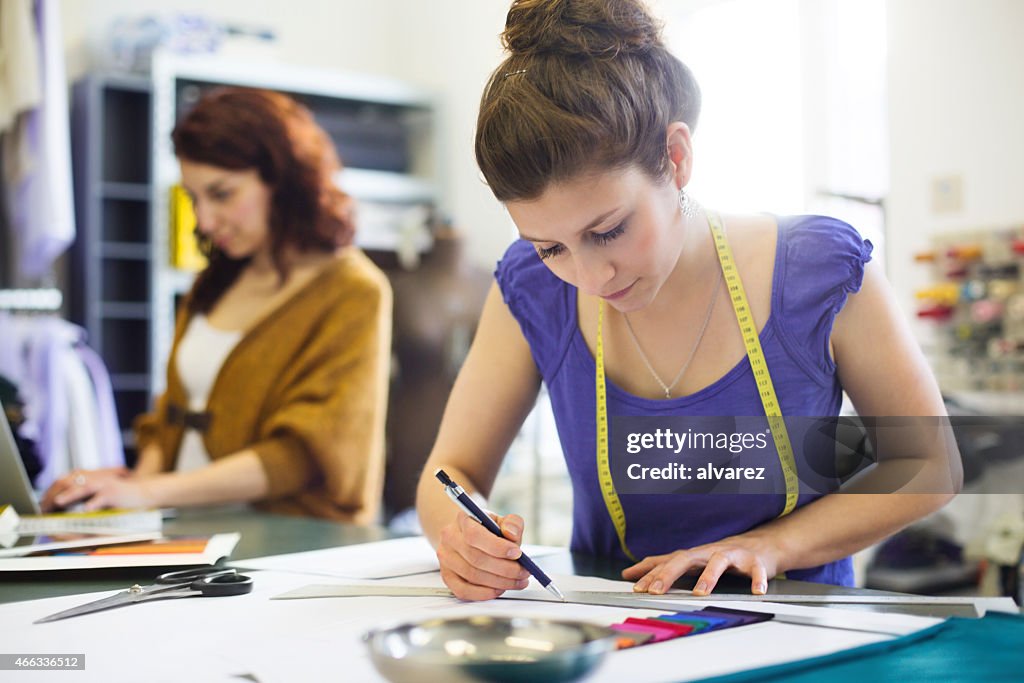 Young fashion designer sketching new dress designs