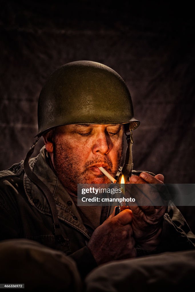 Vintage Army Soldier lighting a cigarette in a fox hole