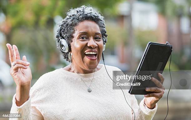 senior black woman using digital tablet, singing - walkman closeup stock pictures, royalty-free photos & images