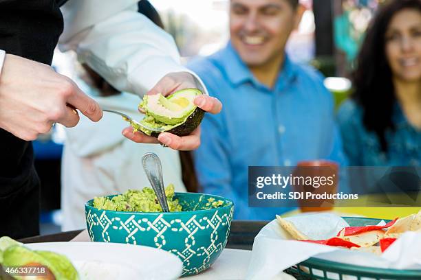 waitress making table side guacamole for customers in restaurant - guacamole stock pictures, royalty-free photos & images