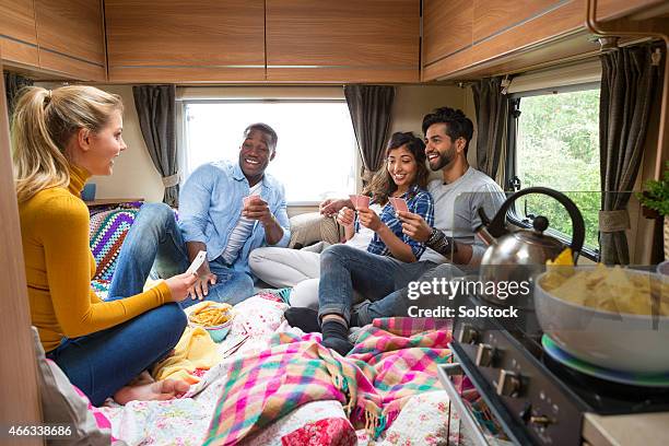 group of friends playing cards in caravan - indoor camping stock pictures, royalty-free photos & images