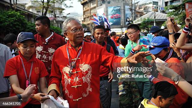 Anti-government protest leader Suthep Thaugsuban receives cash donations and greetings from supporters while marching through Chinatown on February...