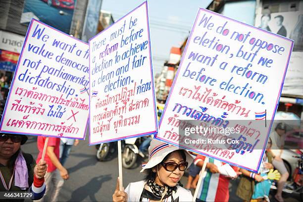 Anti-government protesters hold up signs during a march through Chinatown on February 1, 2014 in Bangkok, Thailand. Voters are due go to the polls on...