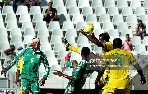 Zimbabwean player Eric Chipeta gets the ball away from Nigerian players during the 2014 African Nations Championship football match between Zimbabwe...