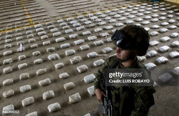 Colombian Army soldier stands next to packages of seized cocaine during a press conference at a Military Base in Bahia Solano, department of Choco,...