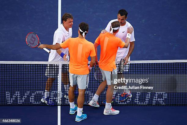 Roger Federer of Switzerland and Michael Lammer of Switzerland congratulate Nenad Zimonjic and Marcin Matkowski of Poland after their doubles win...