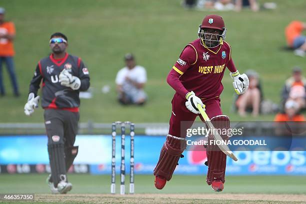 West Indies batsman Johnson Charles runs between the wickets with United Arab Emirates wicket keeper Swapnil Patil in ready during the Pool B 2015...