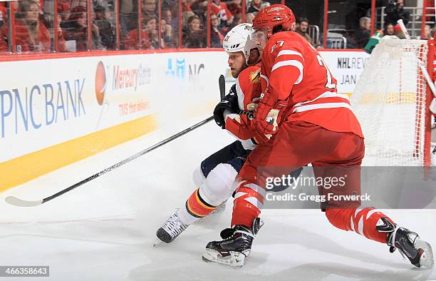 Justin Faulk of the Carolina Hurricanes battles along the boards with Krys Barch of the Florida Panthers during their NHL game at PNC Arena on...