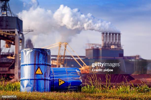 chemical waste drums in front of heavy industry - water pollution stock pictures, royalty-free photos & images