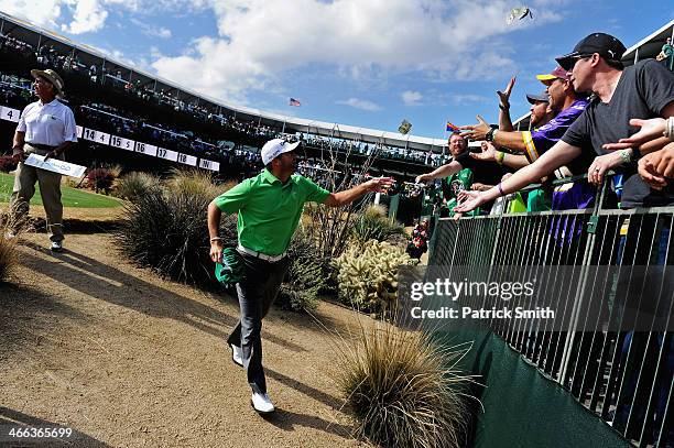 Ryan Palmer throws money to spectators on the 16th hole during the third round of the Waste Management Phoenix Open at TPC Scottsdale on February 1,...