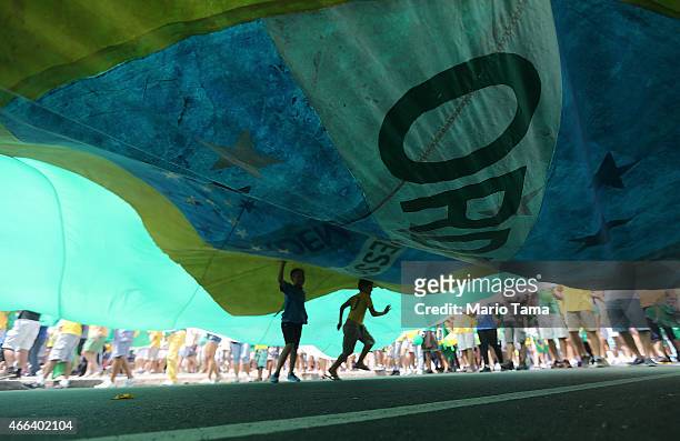 Anti-government protesters carry a large Brazilian flag while marching along Copacabana beach on March 15, 2015 in Rio de Janeiro, Brazil. Protests...