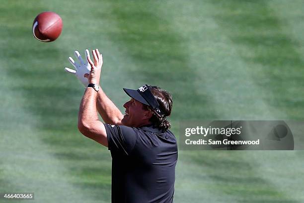 Phil Mickelson throws a football to the crowd on the 16th hole during the third round of the Waste Management Phoenix Open at TPC Scottsdale on...