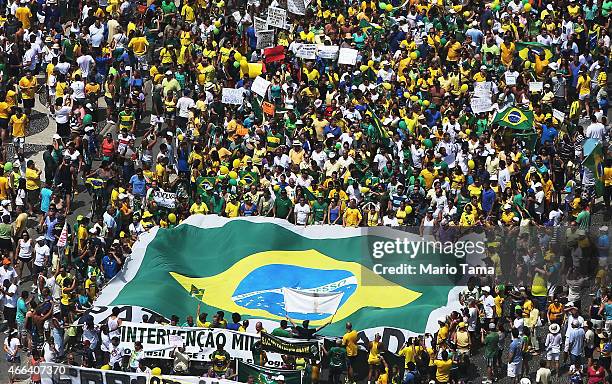 Anti-government protesters march carrying a Brazilian flag along Copacabana beach on March 15, 2015 in Rio de Janeiro, Brazil. Protests across the...