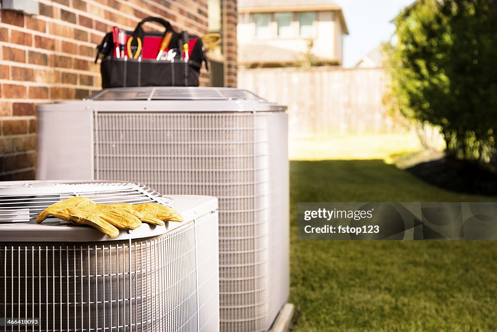 Service Industry: Work tools on air conditioners. Outside residential home.