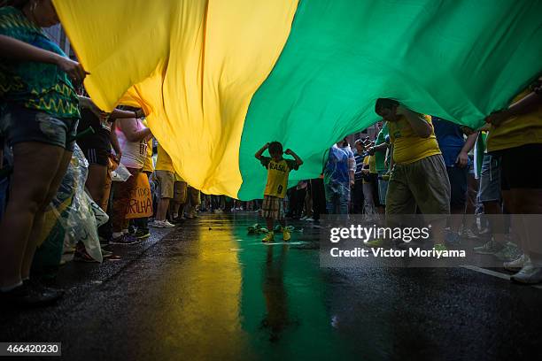 Boy walks under a flag as anti-government protesters march along Avenida Paulista on March 15, 2015 in Sao Paulo, Brazil. Protests across the country...