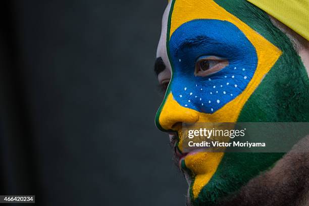 Man with his face painted with the Brazilian flag marches with anti-government protesters along Avenida Paulista on March 15, 2015 in Sao Paulo,...