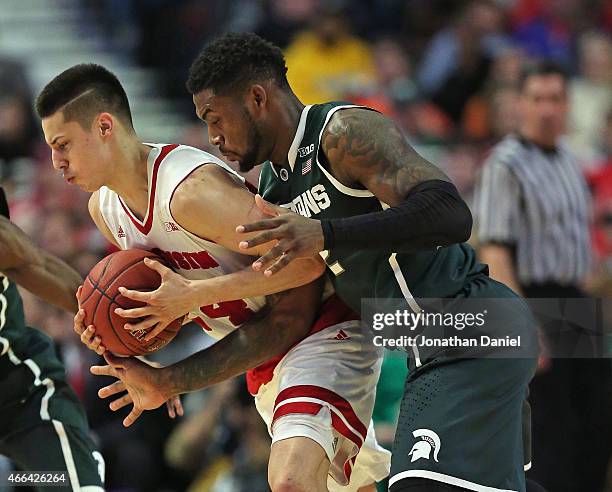 Branden Dawson of the Michigan State Spartans fouls Bronson Koenig of the Wisconsin Badgers as he tries to knock the ball away during the...