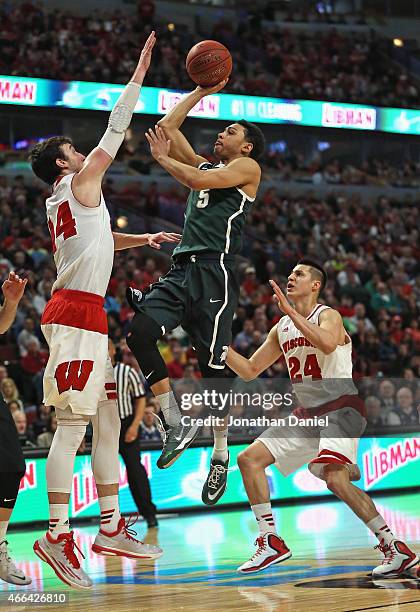 Bryn Forbes of the Michigan State Spartans shoots between Frank Kaminsky and Bronson Koenig of the Wisconsin Badgers during the Championship game of...