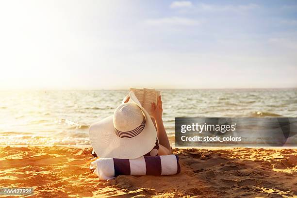 leyendo en la playa - sombrero de sol fotografías e imágenes de stock