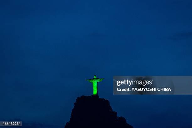 View of the statue of Christ the Redeemer illuminated in green to celebrate the upcoming Irish festivity of Saint Patrick's Day, atop Corcovado hill...