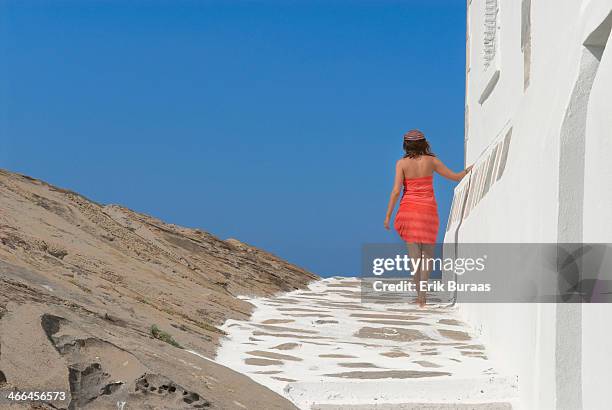 girl in red dress walking along white building - erik buraas stock-fotos und bilder