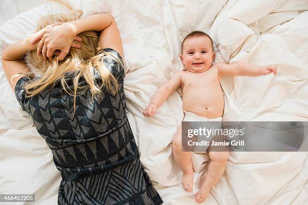 mother exhausted in bed next to baby - mom head in hands stock pictures, royalty-free photos & images