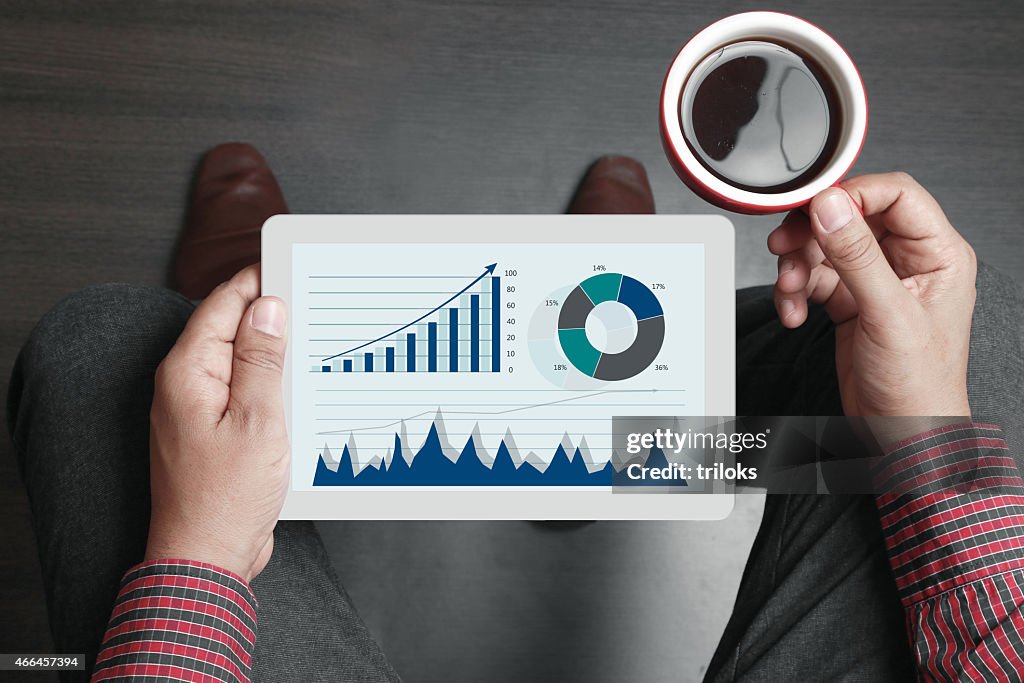 Businessman holding tea cup and digital tablet