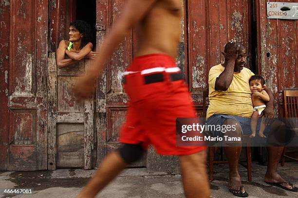 Residents Lourdes Vieira, Antonio Steves and Pietra Steves look on as people march in the first street parade of the 2014 Carnival season through the...