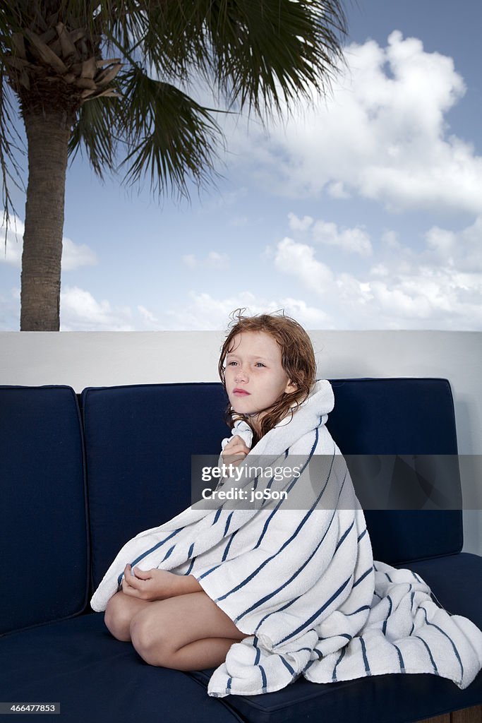Girl sitting at poolside cover with towel