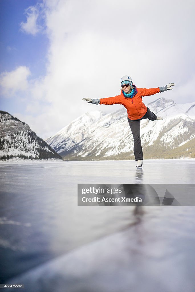 Woman figure skates across mountain pond