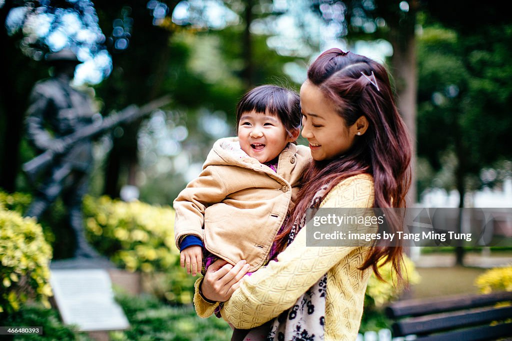 Mom & toddler girl talking joyfully in park