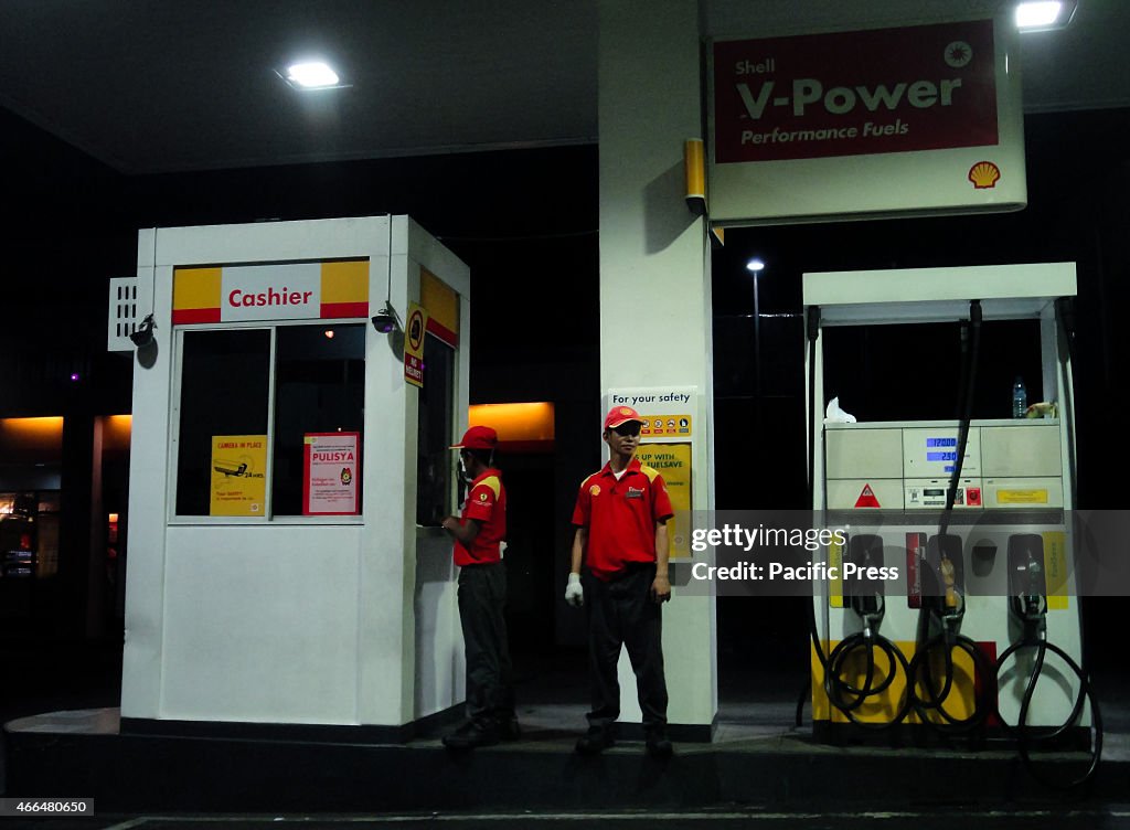 Filipino gas station attendants stand by at a gas station...