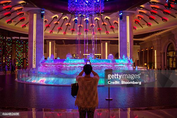 Visitor takes a photograph in the lobby of the Galaxy Macau casino resort, operated by Galaxy Entertainment Group Ltd., in Macau, China, on Monday,...
