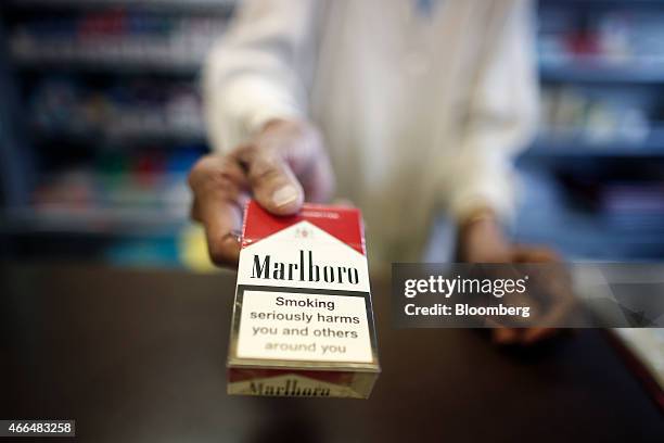 Smoking Kills" logo sits on a packet of Marlboro cigarettes, produced by Philip Morris International Inc., a unit of Altria Inc., as a shopkeeper...