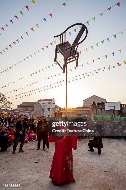 Stuntman balances a wooden chair on his chin during a show to mark the Lantern Festival on March 04, 2015 in Huaxian, China. PHOTOGRAPH BY Feature...