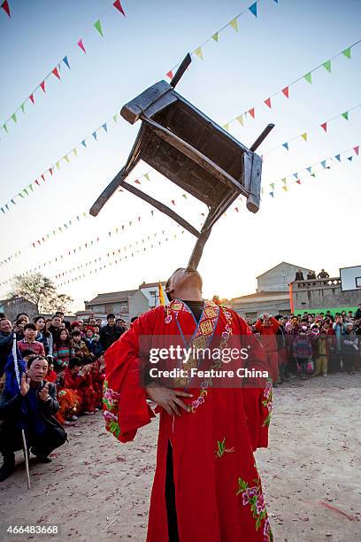 Stuntman balances a wooden chair on his chin during a show to mark the Lantern Festival on March 04, 2015 in Huaxian, China. PHOTOGRAPH BY Feature...