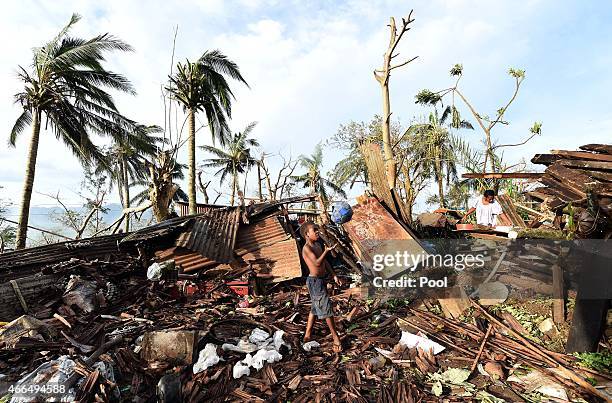 Young boy plays with a ball as his mother searches through the ruins of their family home on March 16, 2015 in Port Vila, Vanuatu. Cyclone Pam has...