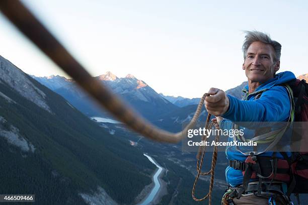 climber pulls rope tight for teammate - begeleiding stockfoto's en -beelden