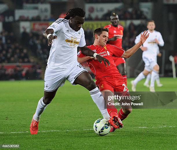 Joe Allen of Liverpool competes with Bafetimbi Gomis of Swansea City during the Barclays Premier League match between Swansea City and Liverpool at...