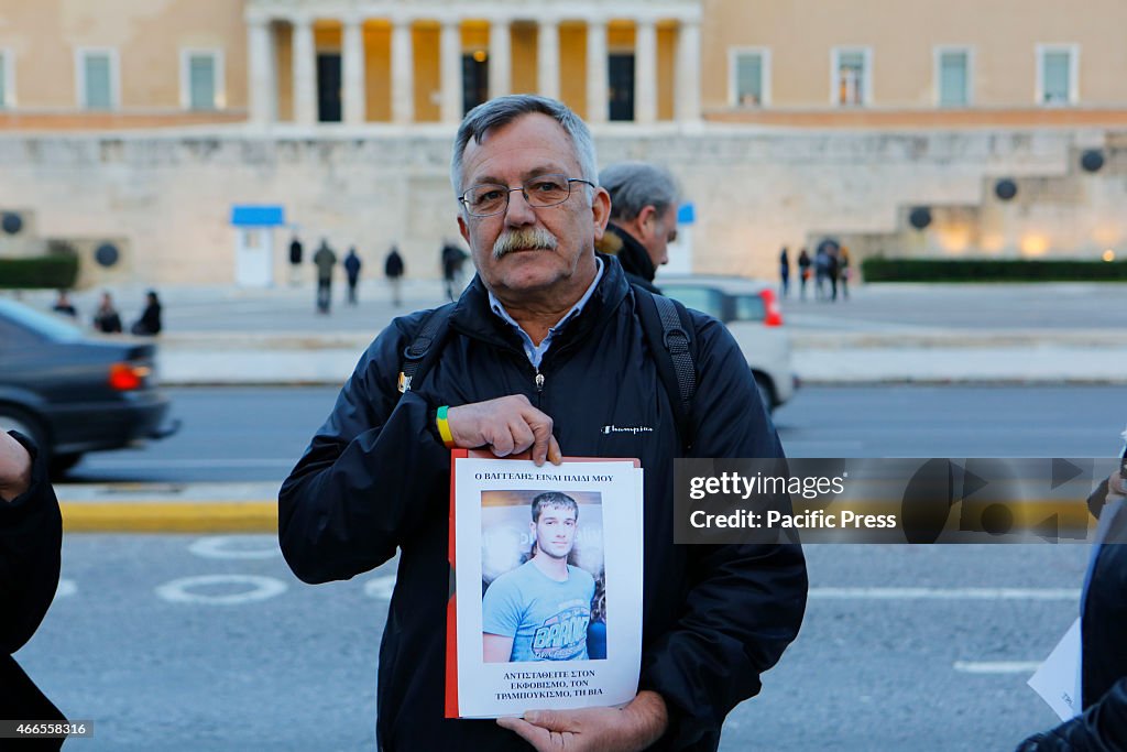 A man holds up a poster with a picture of Vangelis...