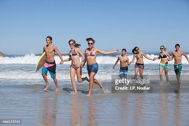 teens running on the beach - a group of young teenage boys and girls running at the beach stock pictures, royalty-free photos & images