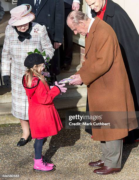 Queen Elizabeth II and Prince Philip, Duke of Edinburgh meet a young girl after attending church at West Newton on February 2, 2014 in King's Lynn,...