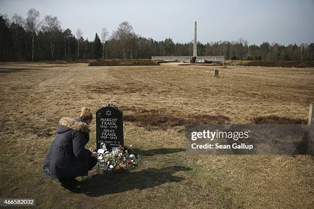 Young woman on a school excursion kneels at a tombstone that commemorates Anne Frank and her sister Margot on the site of the former Bergen-Belsen...