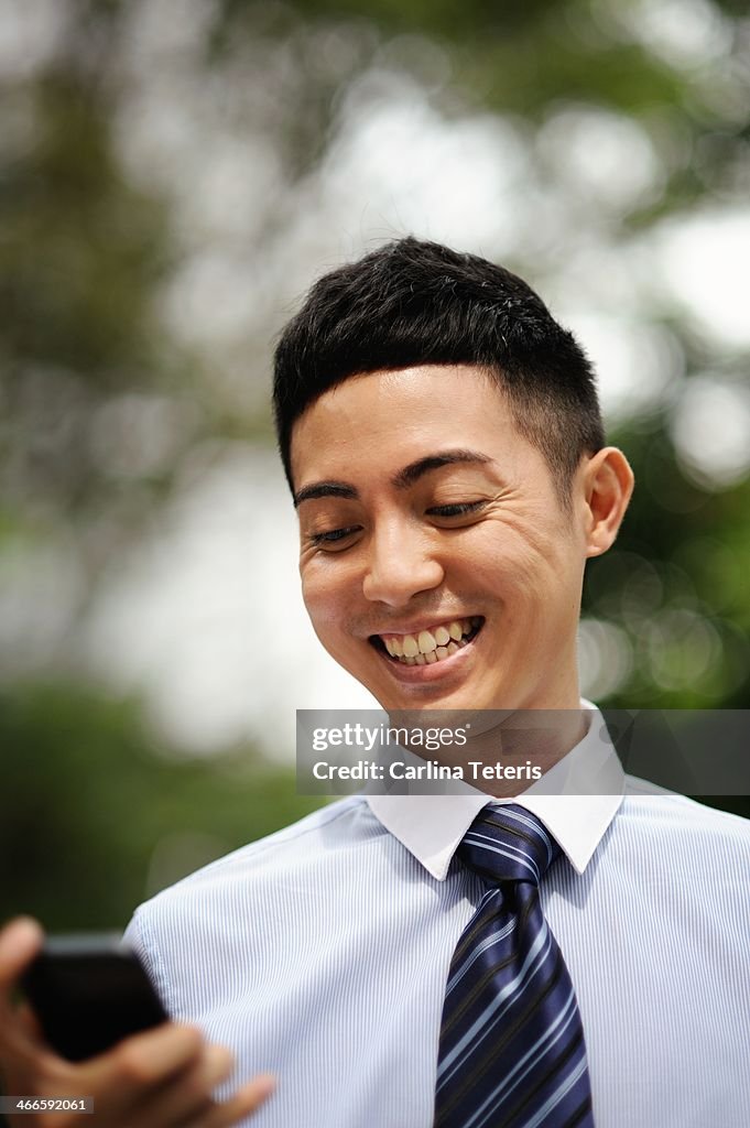 Young business man smiling and checking his phone