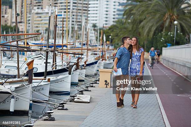 man kissing his girlfriend & walking by sailboats - kiss booth stock-fotos und bilder