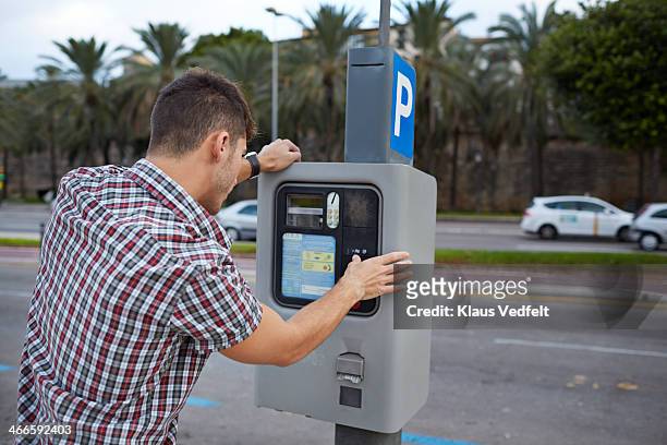 man feeding parking meter - パーキングメーター ストックフォトと画像
