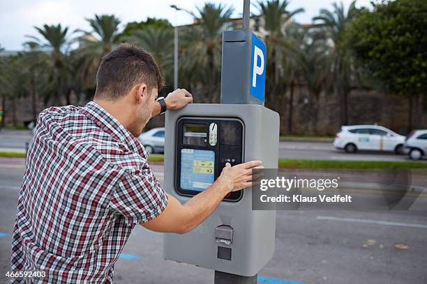 man feeding parking meter - parquímetro imagens e fotografias de stock