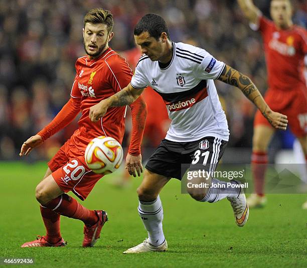 Adam Lallana of Liverpool competes with Ramon Motta of Besiktas during the UEFA Europa League Round of 32 match between Liverpool FC and Besiktas JK...