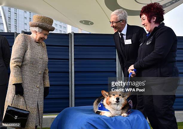 Britain's Queen Elizabeth II looks at a Corgi dog as British television presenter Paul O'Grady looks on during the opening of the new Mary Tealby dog...