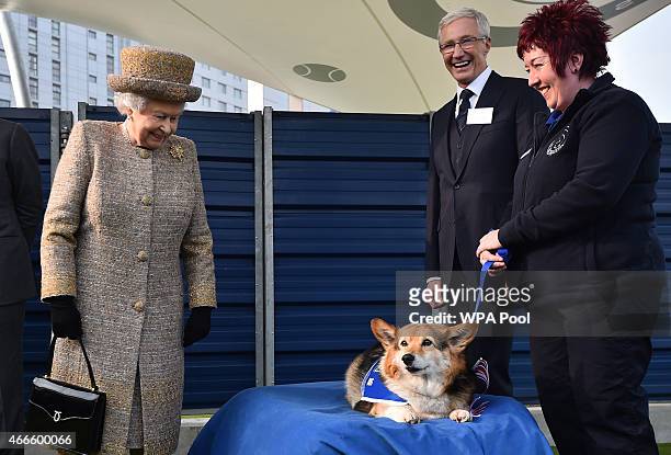 Britain's Queen Elizabeth II looks at a Corgi dog as British television presenter Paul O'Grady looks on during the opening of the new Mary Tealby dog...
